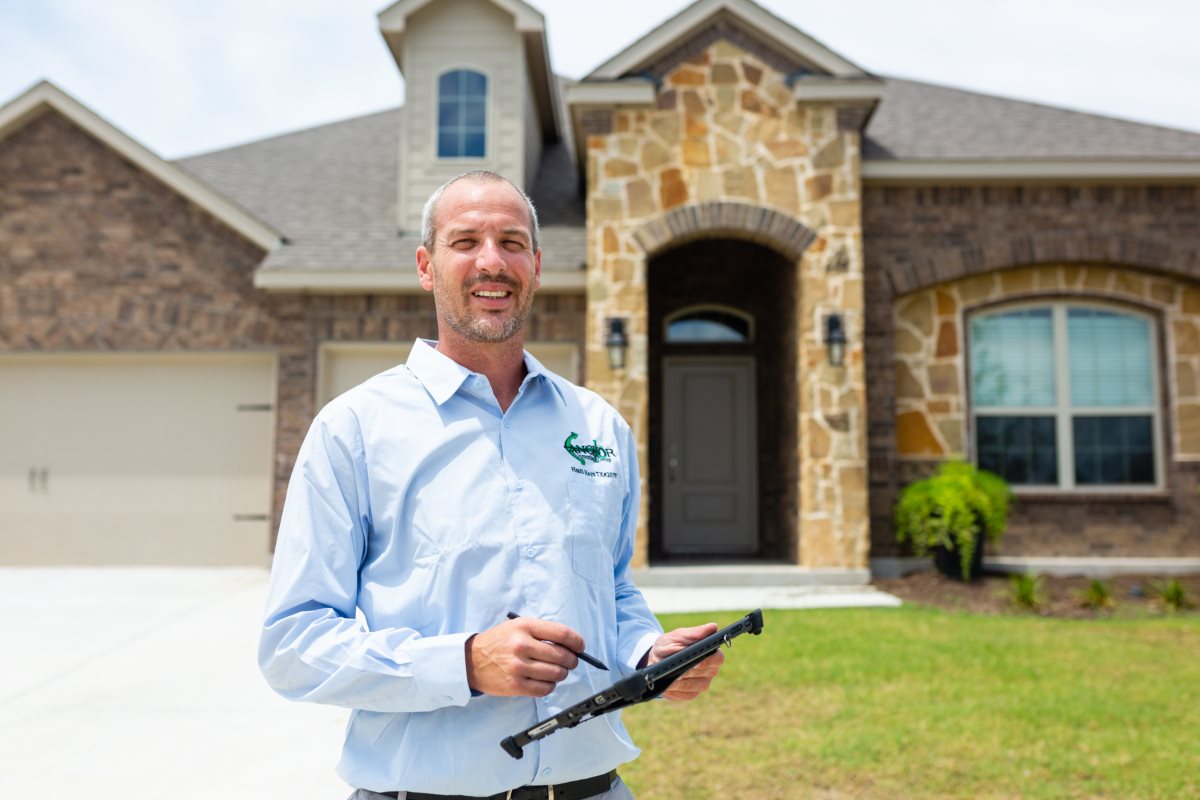 Heath Hays, Owner/President of Anchor Inspection Group, holding an inspection tablet in front of a North Texas home